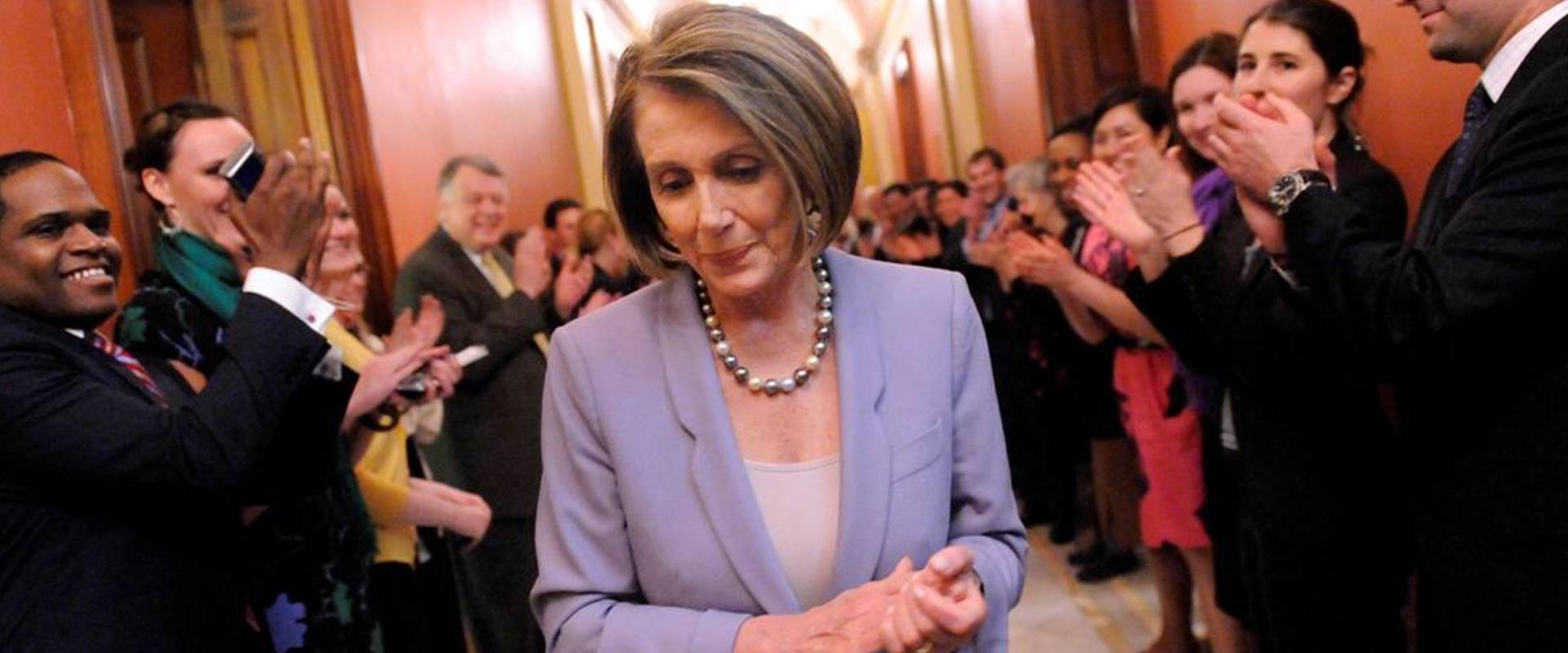 Speaker Pelosi smiles in hallway with staff clapping after passage of the affordable care act